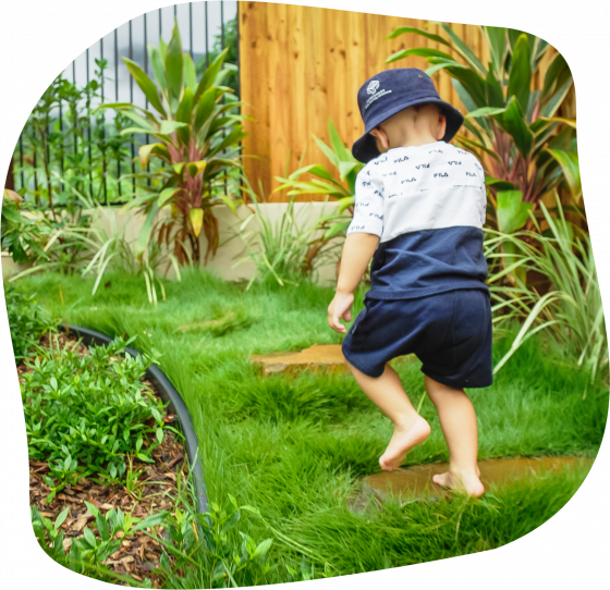 Two young children wearing blue hats playing with water in a container outdoors.