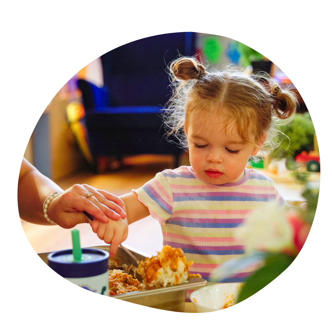 Young child self serving food at a table