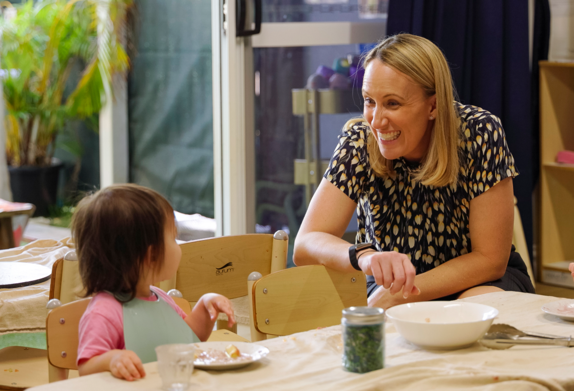 A child and adult sitting at a small table during a meal time