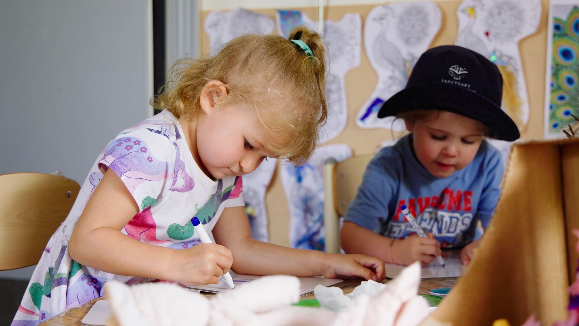 two young children sitting at table drawing