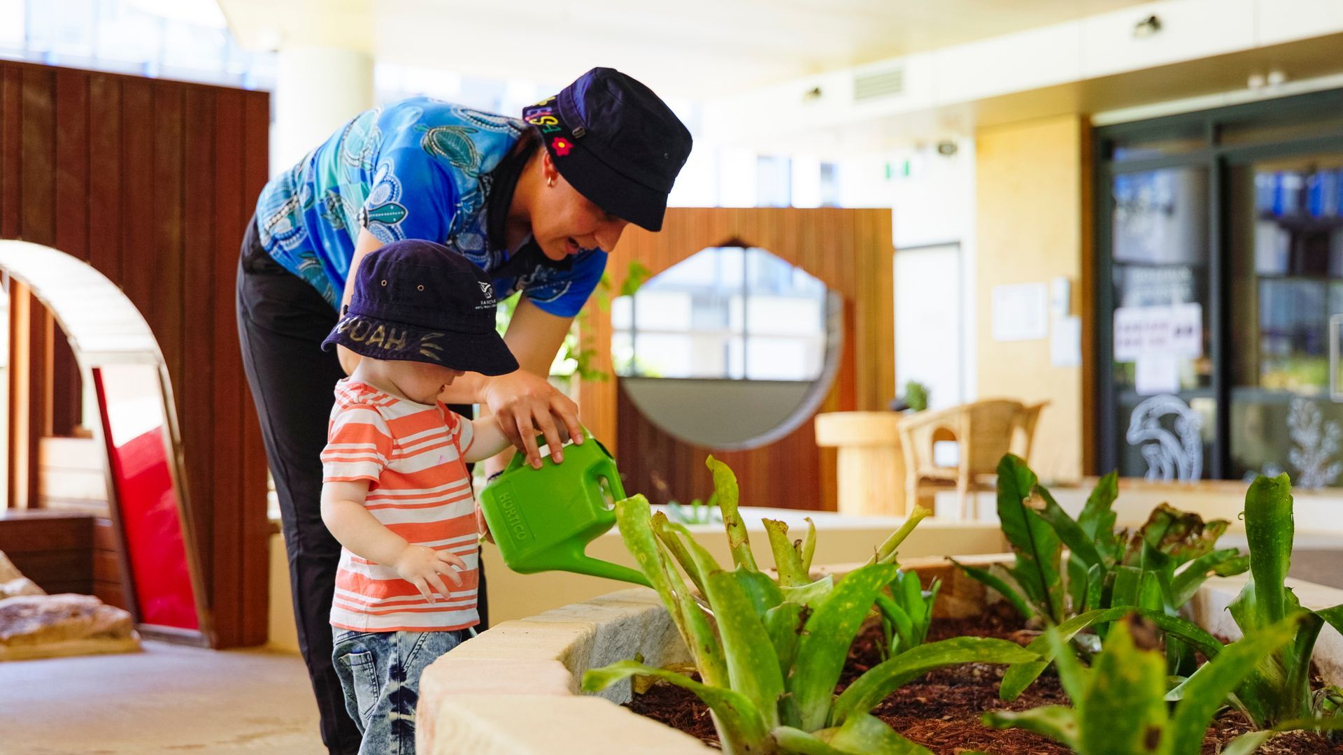 educator and young child watering plants outdoors together