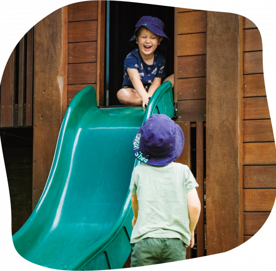Child laughing while someone holds their foot, another child watches.