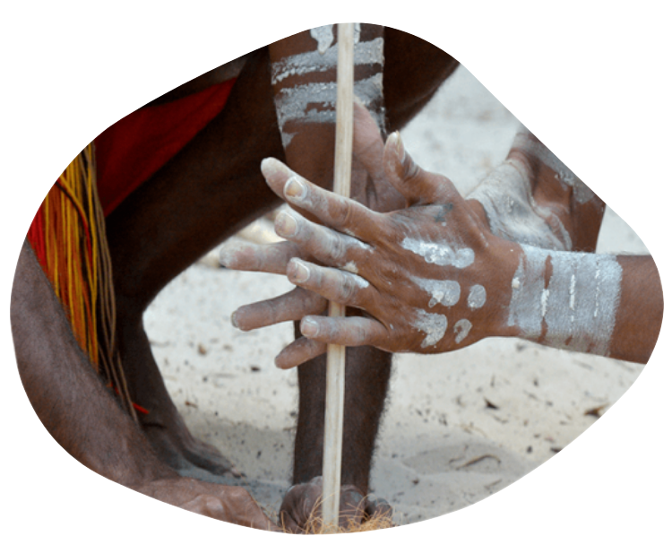 Hands painted with white markings using a drill on a wooden stick outdoors.