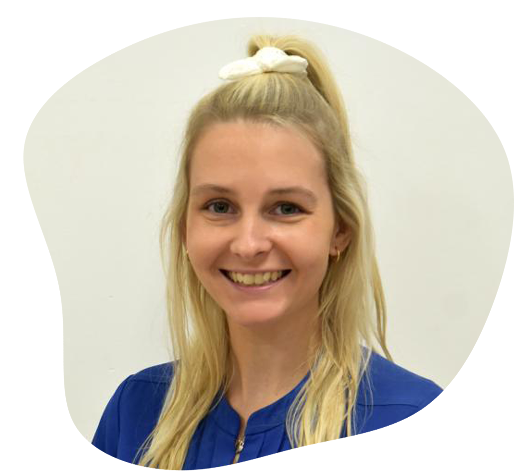 Blonde woman smiling, wearing a blue shirt, hair up in a ponytail with a white bow.