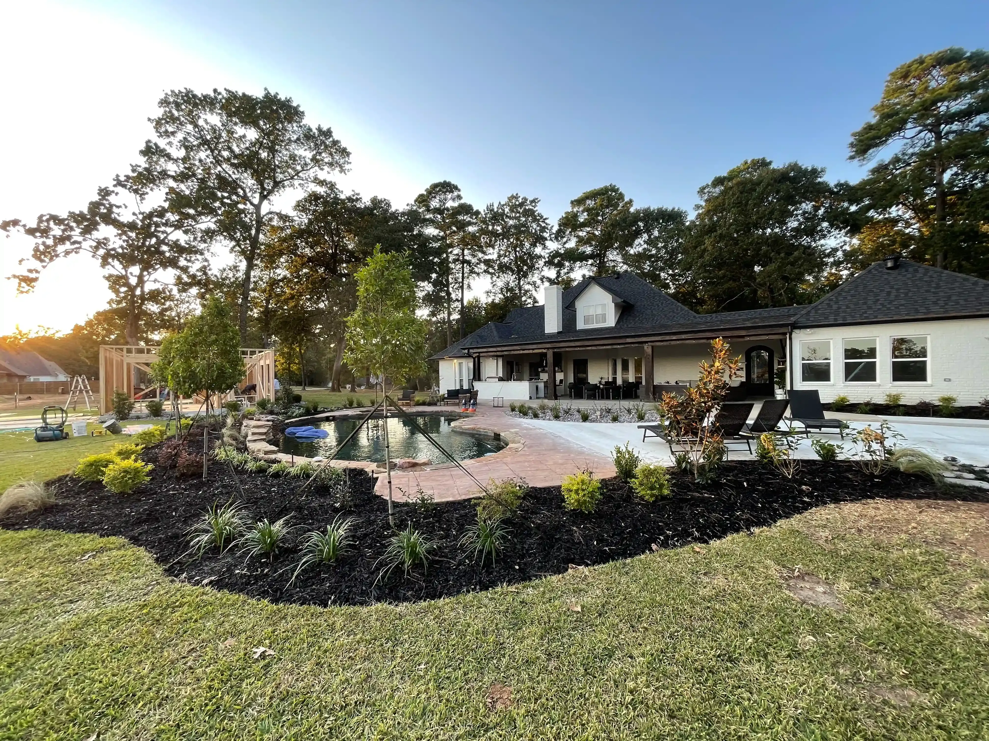 A lawn with flowers and a brick wall in the background