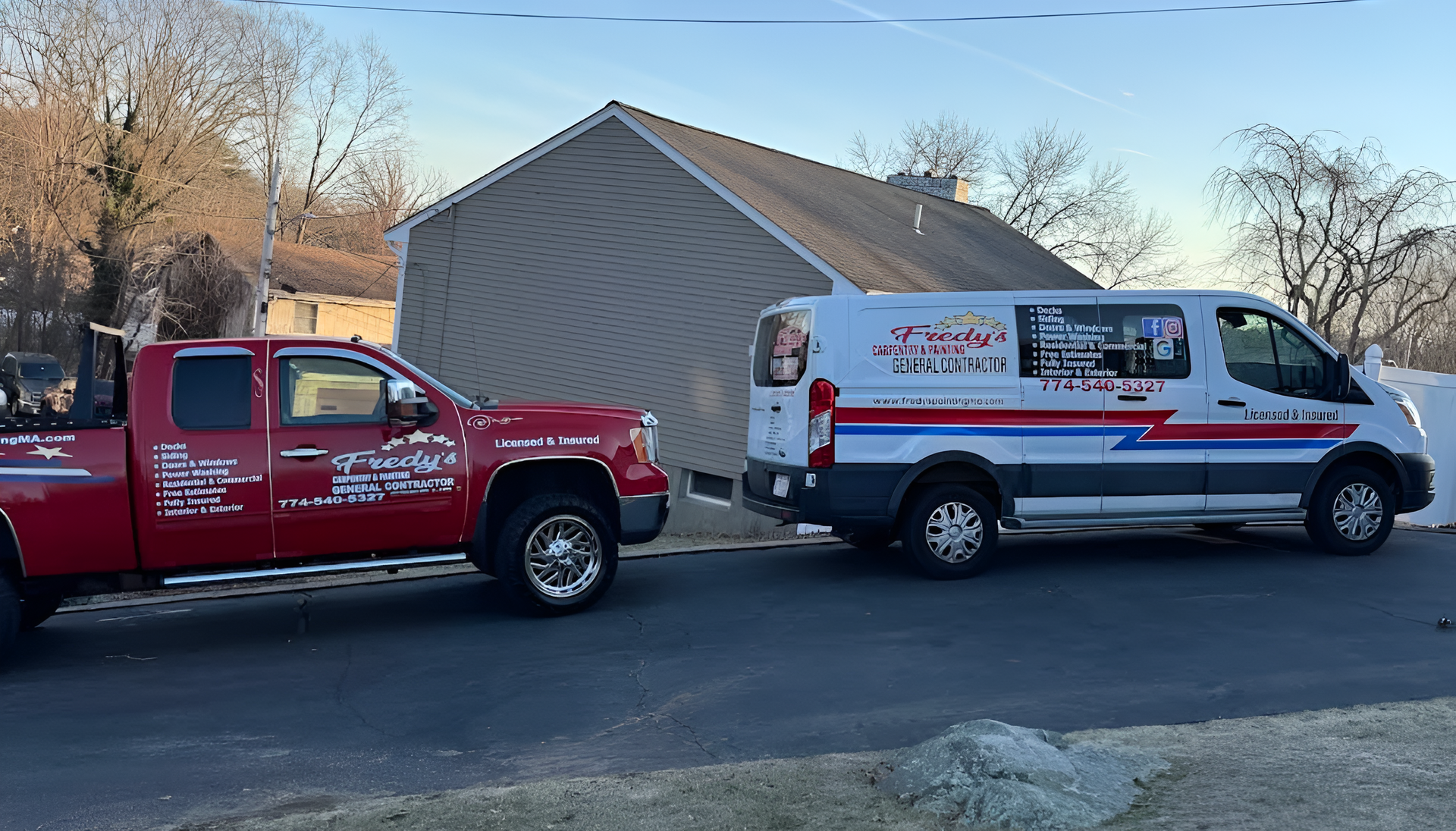 Red pickup truck and white service van parked on a driveway near a house.