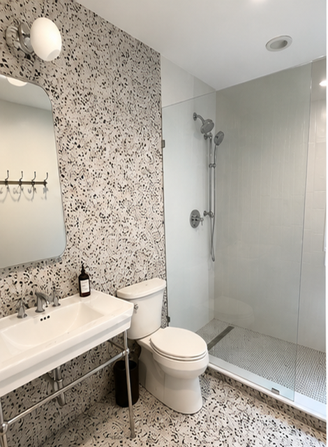 Bright bathroom with patterned wallpaper, white sink and toilet, and a glass shower stall.