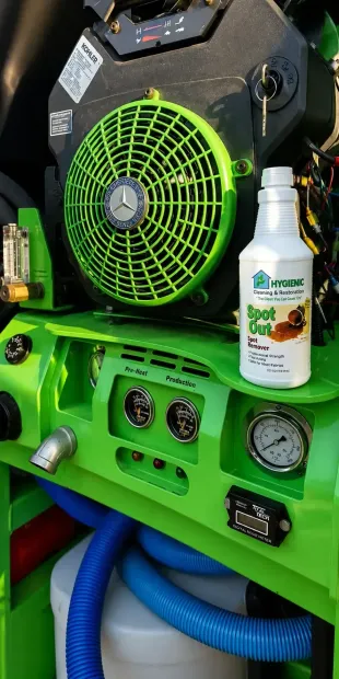 Green air compressor with gauges, hose, and a bottle of cleaner attached to the front panel.