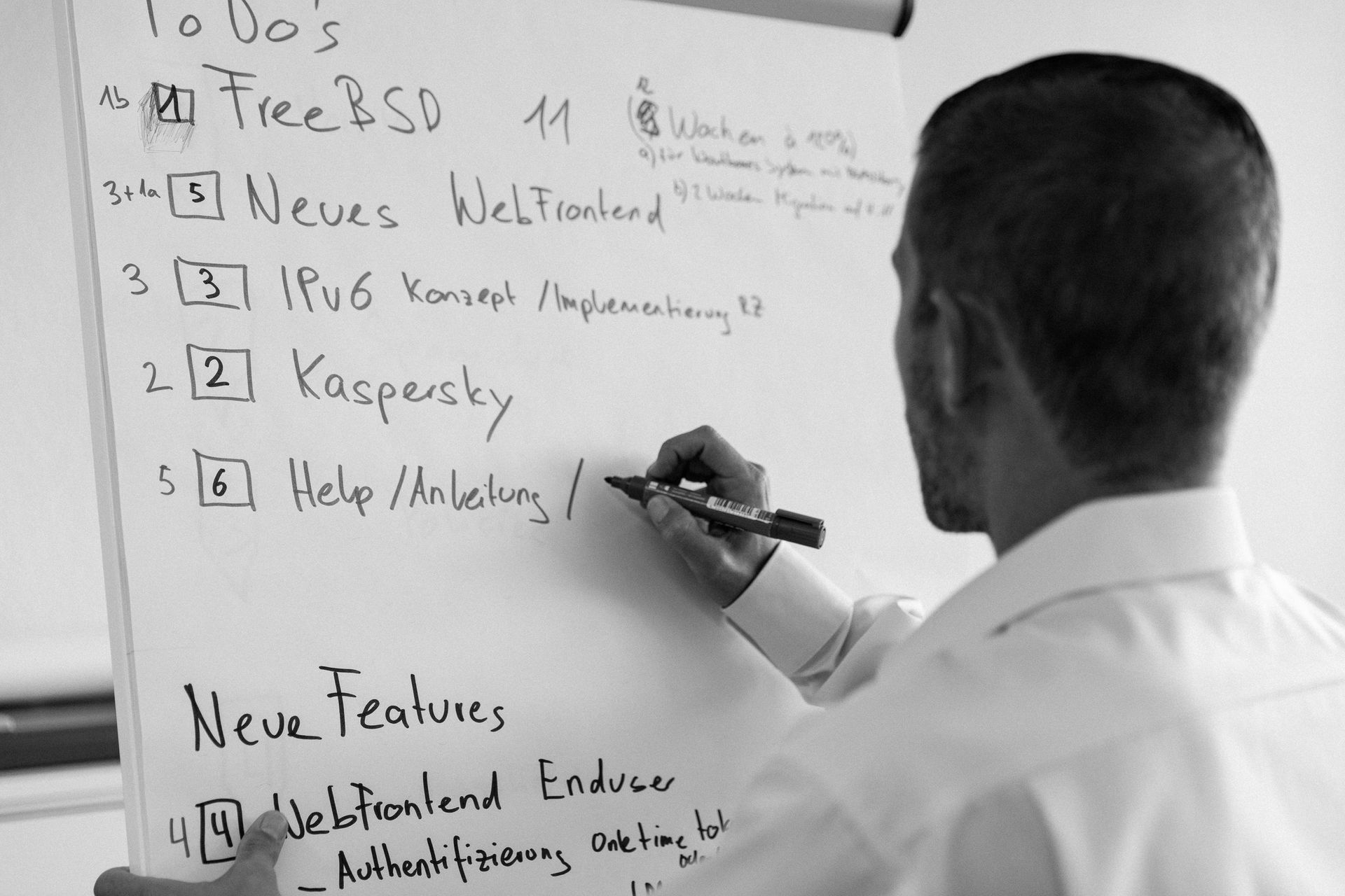 Person schreibt während einer Besprechung oder Präsentation mit einem Marker auf ein Whiteboard