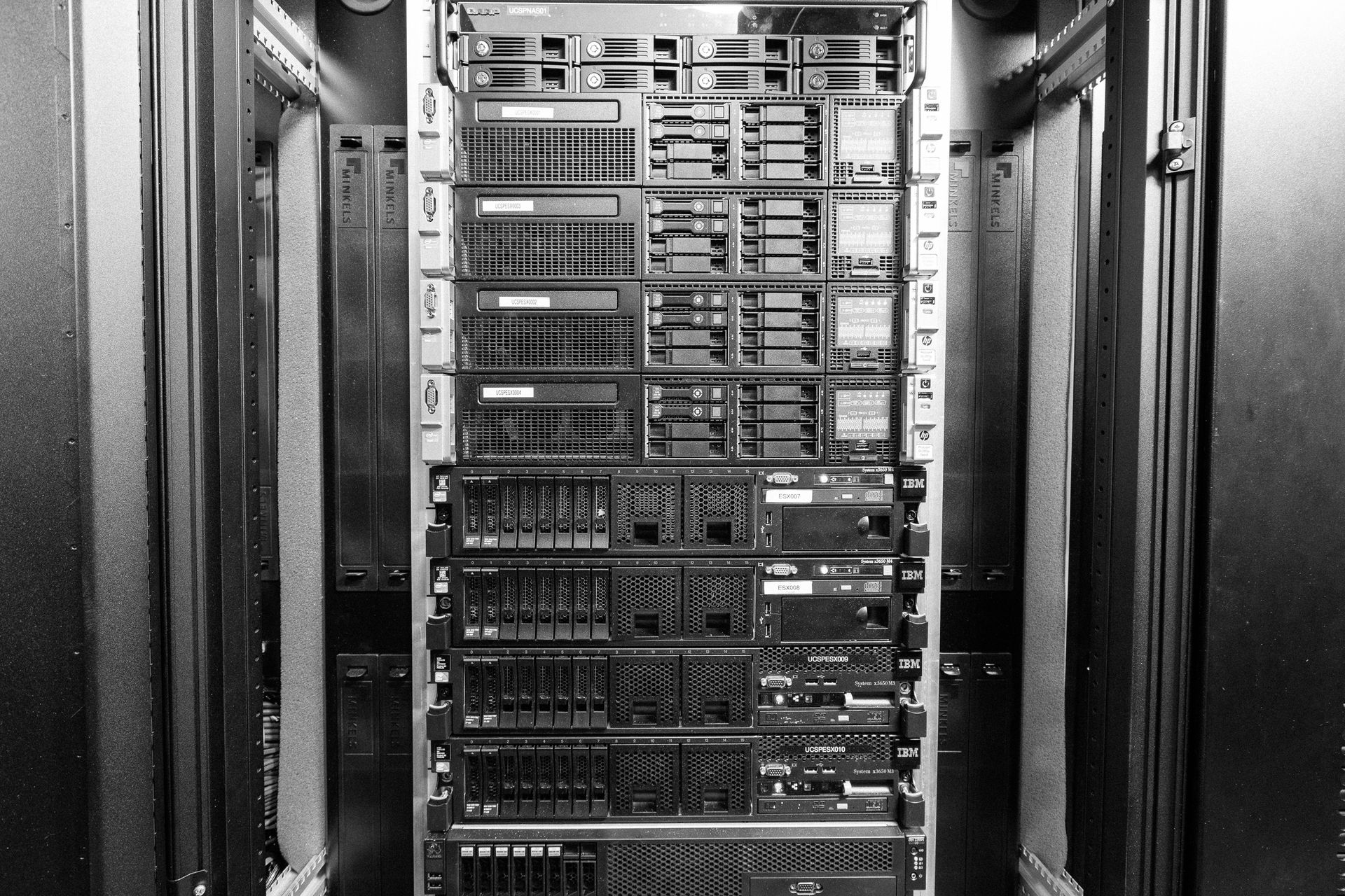 Schwarz-weißer Serverschrank in einem Rechenzentrumsflur, gefüllt mit gestapelter Computerausrüstung.