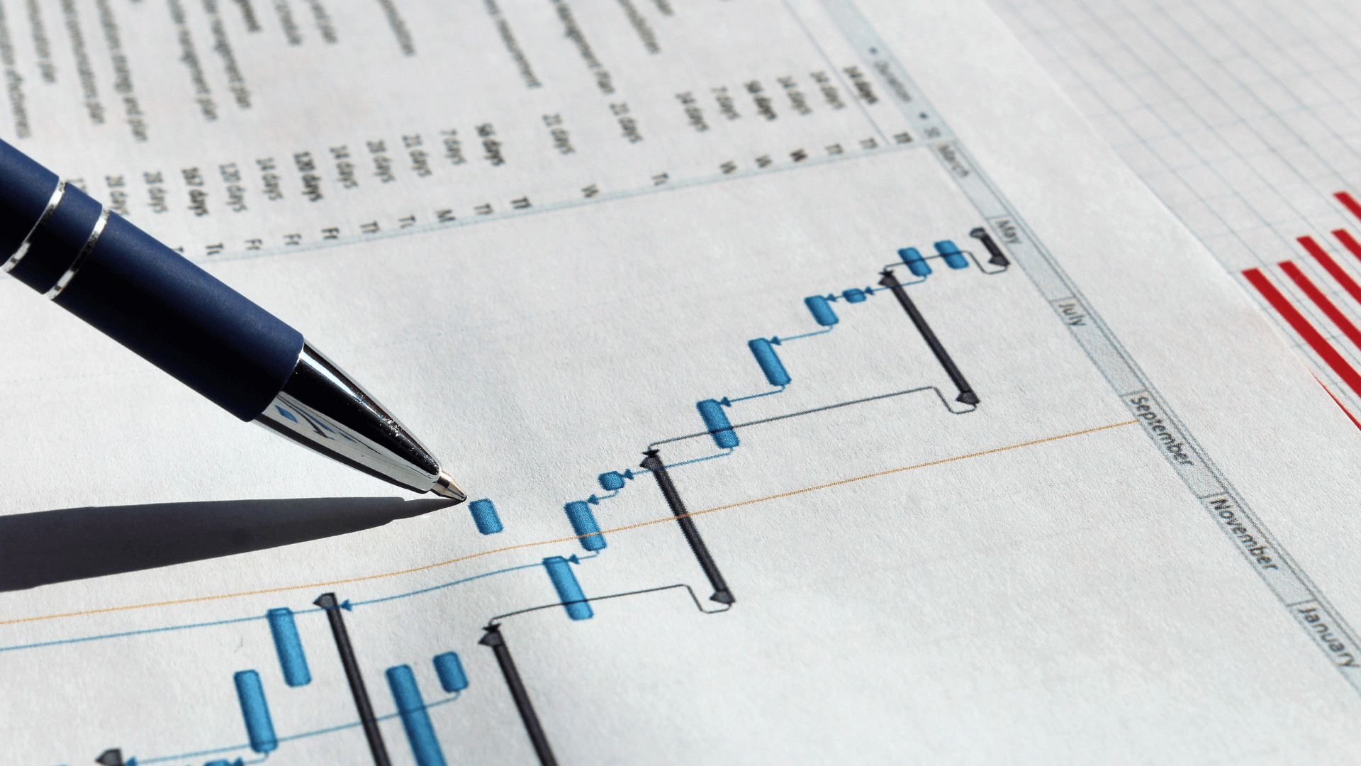 Ein Stift zeigt auf ein steigendes blaues Balkendiagramm in einem Finanzbericht