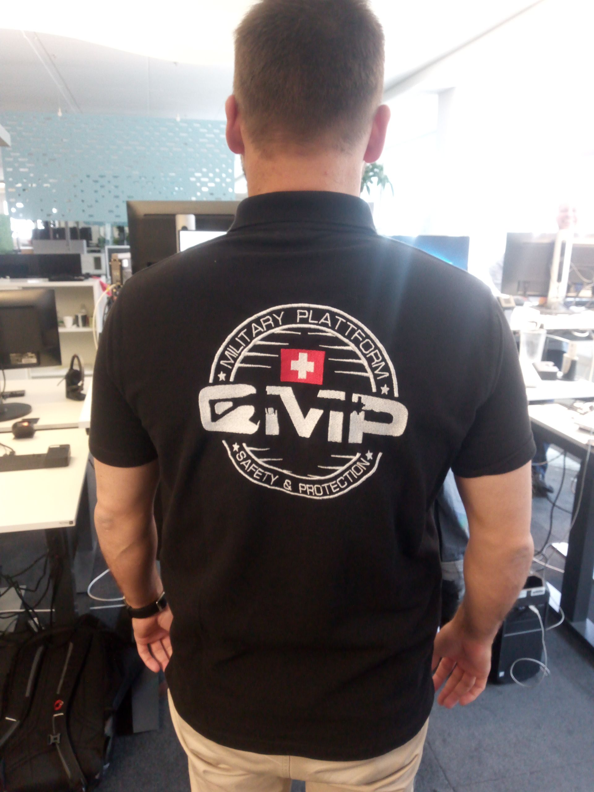 Person in schwarzem CVS-Poloshirt, von hinten in einem Büro zu sehen.