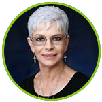 A woman with short gray hair and glasses is wearing a black shirt and earrings.