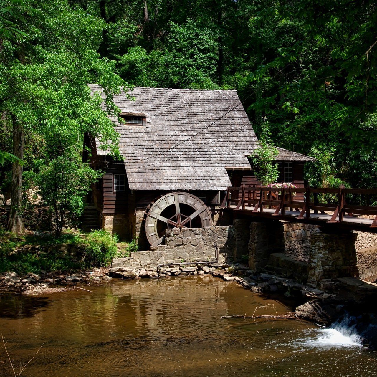 A small house with a water wheel in front of it