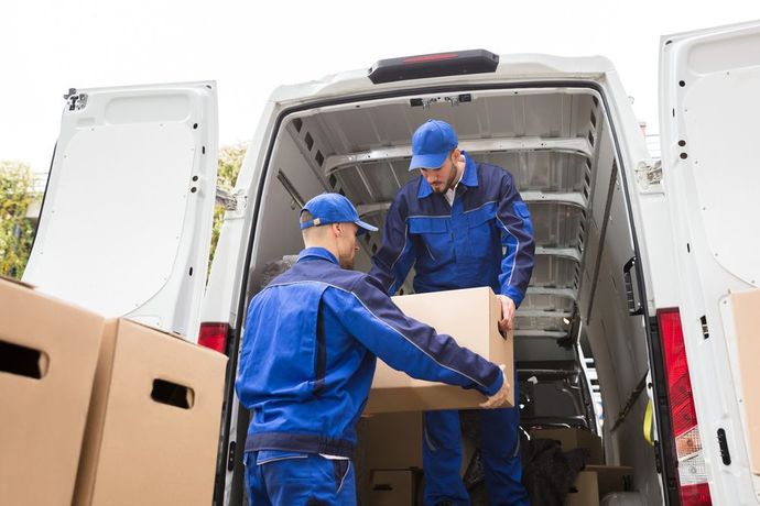 Two men are loading boxes into a van.