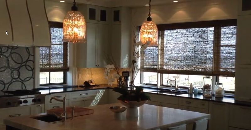 A elegant kitchen has woven wood shades on the windows.