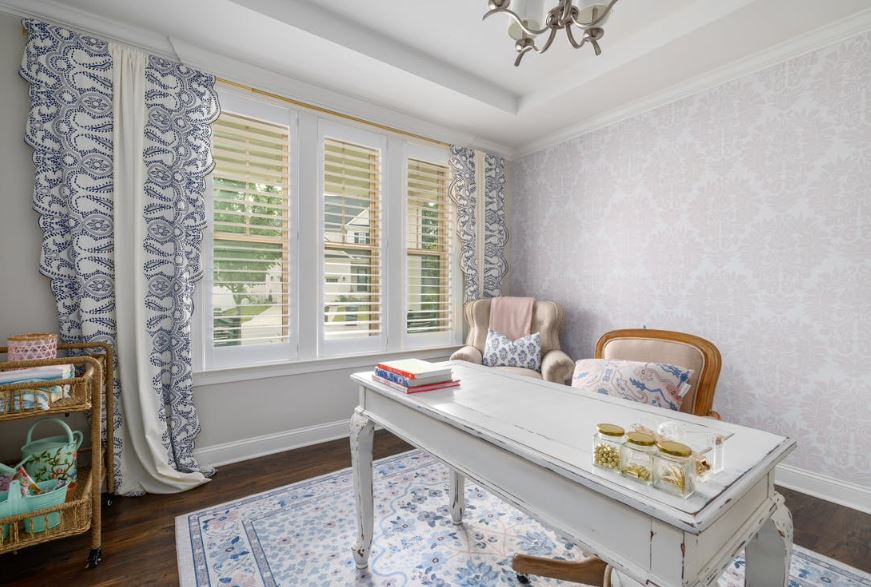 A home office with a white desk , chair , and rug.