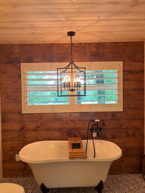 A bathroom with a bathtub and a window with shutters.