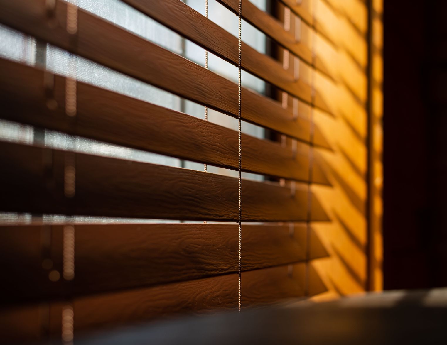 Wooden blinds casting shadows, lit by sunlight.
