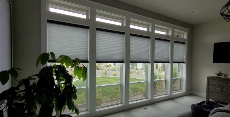 A bedroom with a wall of windows has cellular shades to regulate natural light.