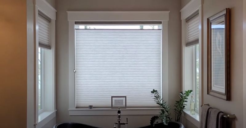 A bathroom with a tub and a window with blinds.