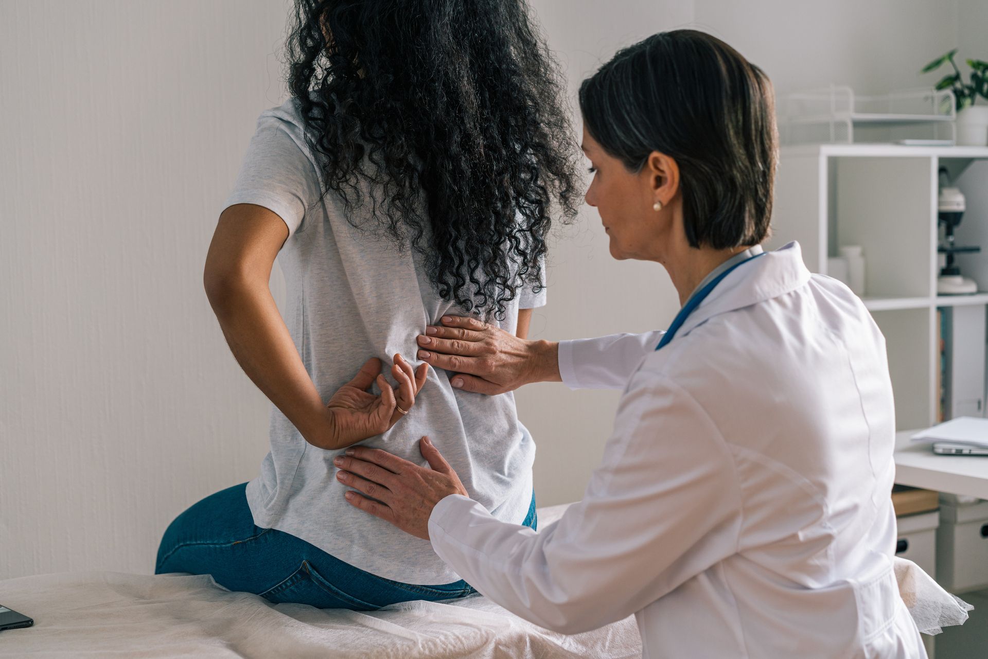 Doctor examining a patient's lower back in an office setting.
