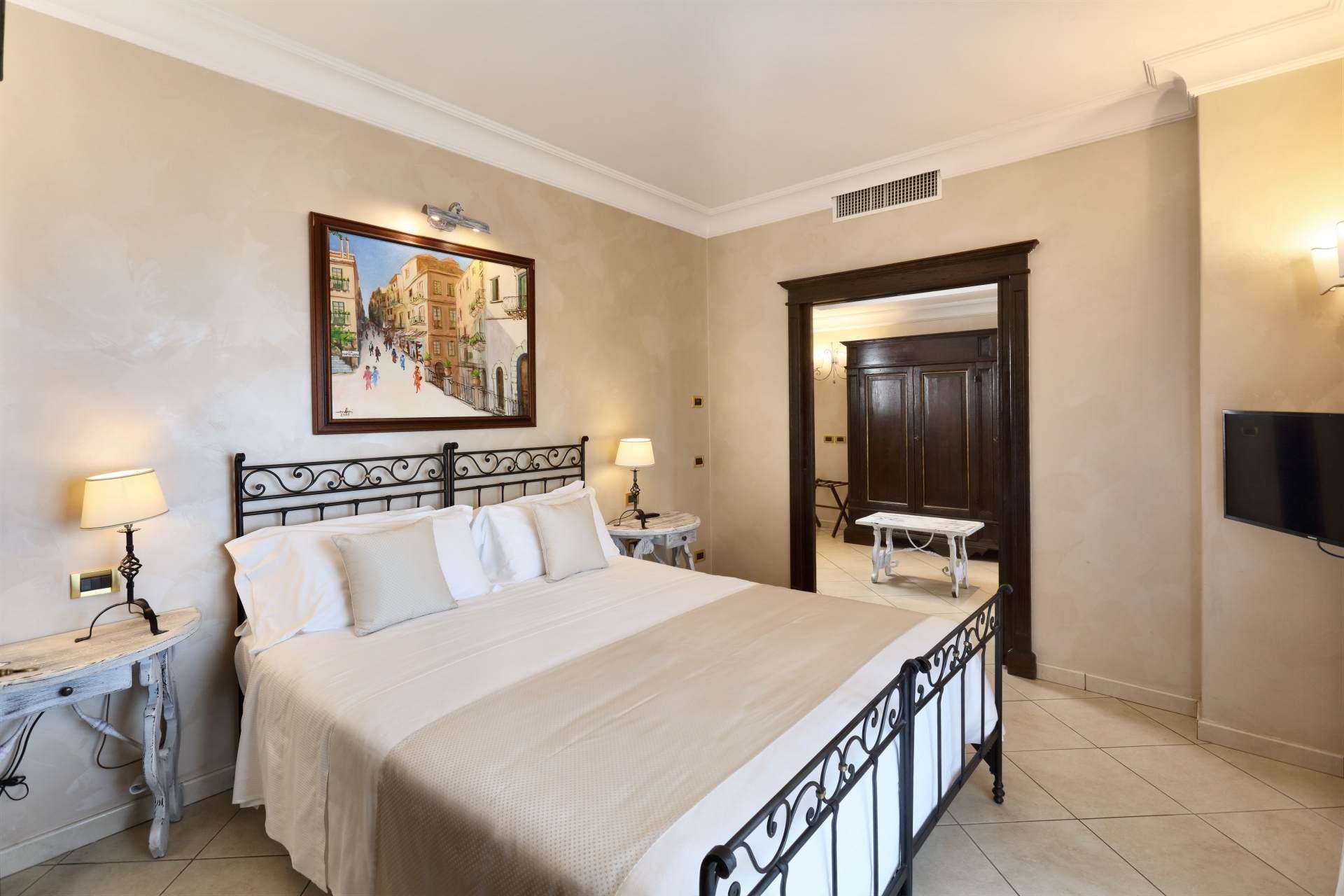 Ein Schlafzimmer mit einem großen Bett und einem Bild an der Wand darüber.