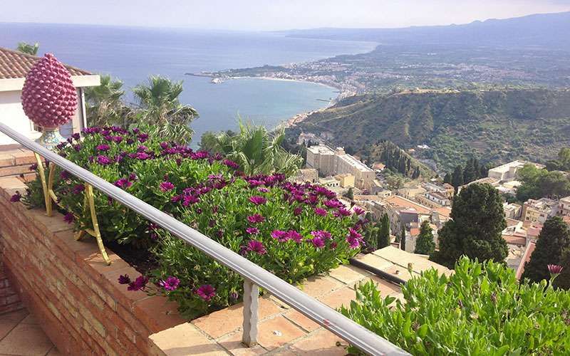 Ein Balkon mit Blumen und Blick auf das Meer.