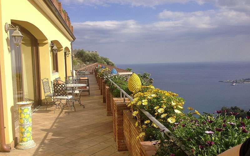 Ein Balkon mit Tischen und Stühlen und Blick auf das Meer.