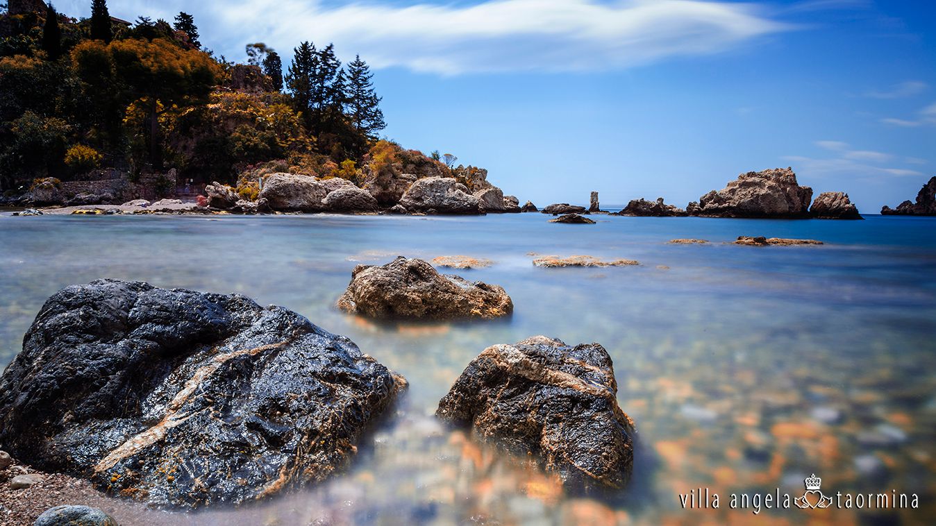 Ein Strand mit Felsen im Wasser und Bäumen im Hintergrund