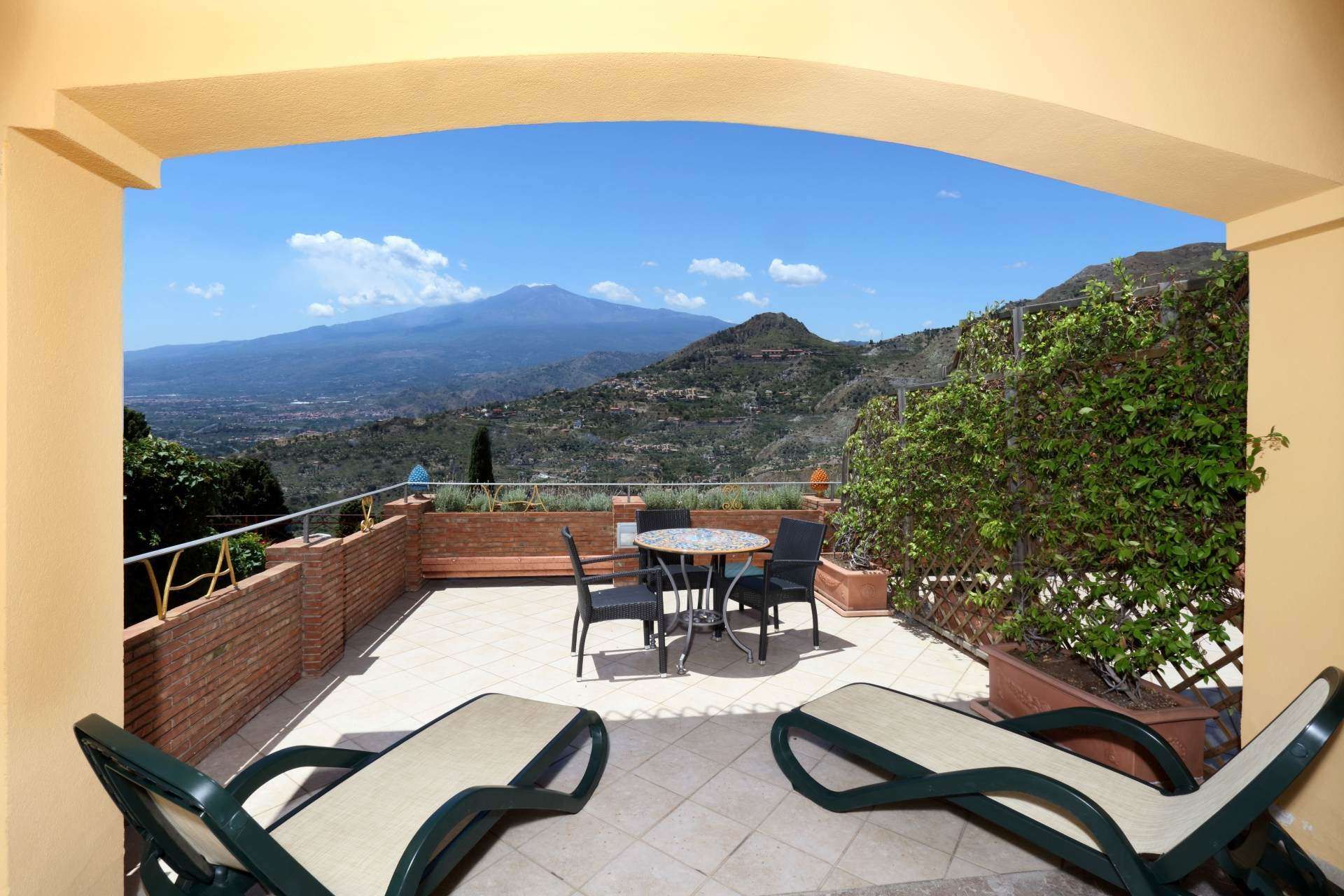 Eine Terrasse mit Stühlen und einem Tisch mit einem Berg im Hintergrund