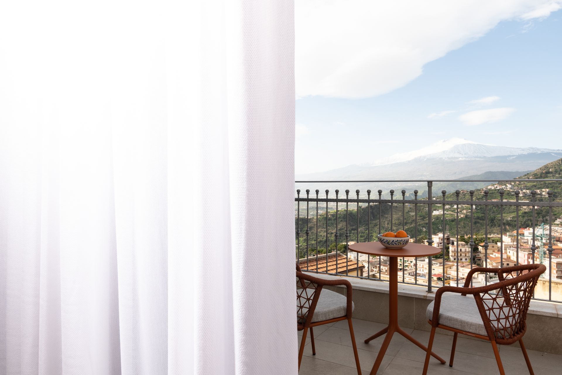 Ein Balkon mit Tisch und Stühlen und Blick auf die Stadt.