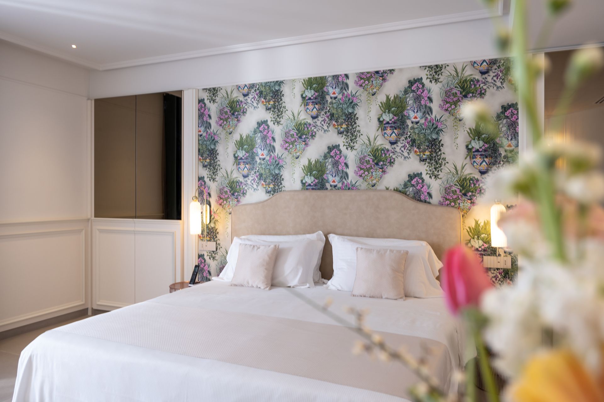 Ein Hotelzimmer mit einem großen Bett und Blumen im Vordergrund.