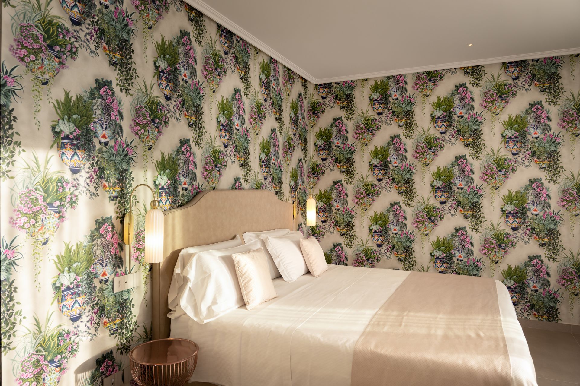 Ein Schlafzimmer mit Bett, Nachttisch und geblümter Tapete.