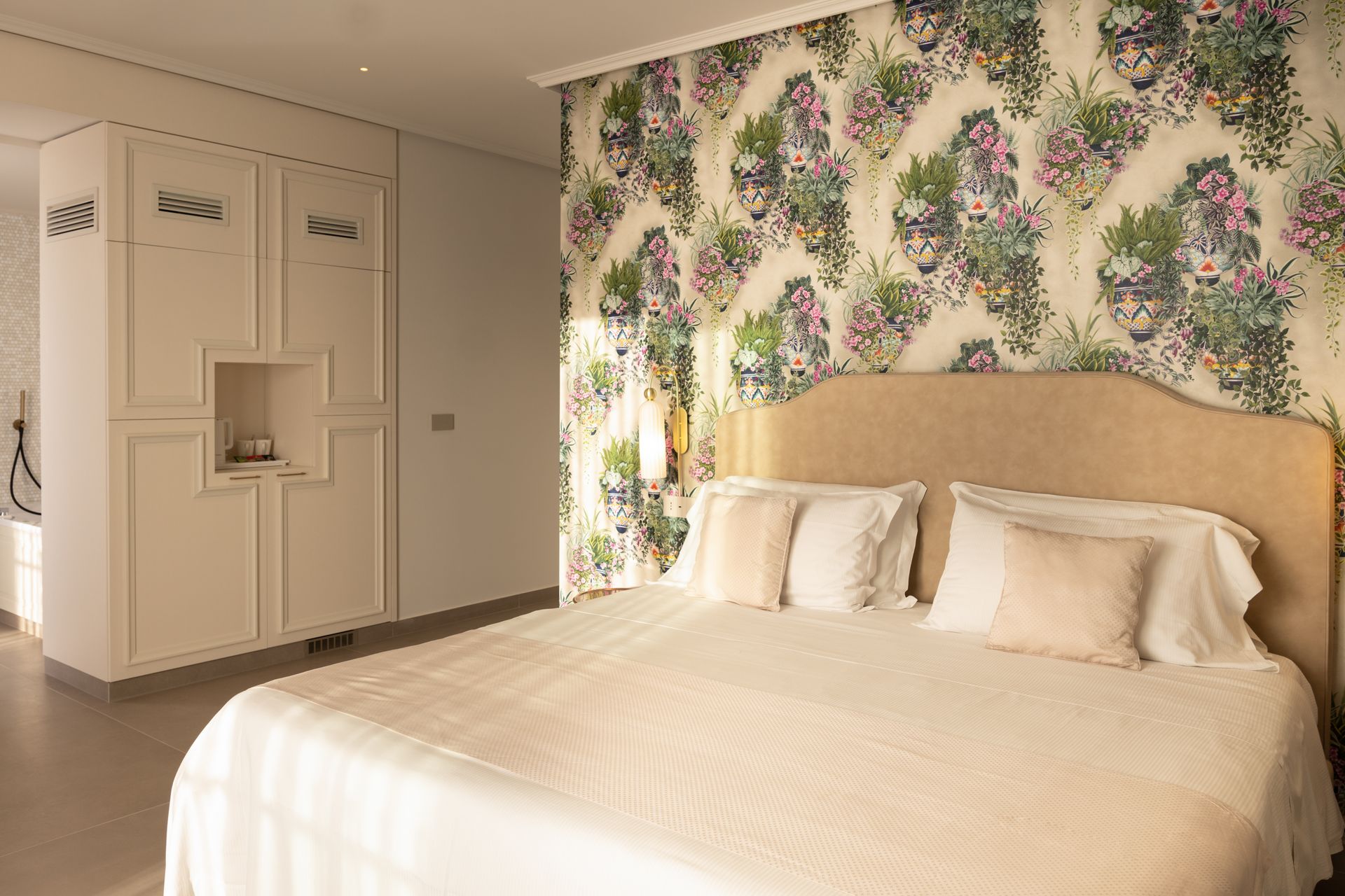 Ein Schlafzimmer mit einem großen Bett und einer Blumentapete an der Wand.