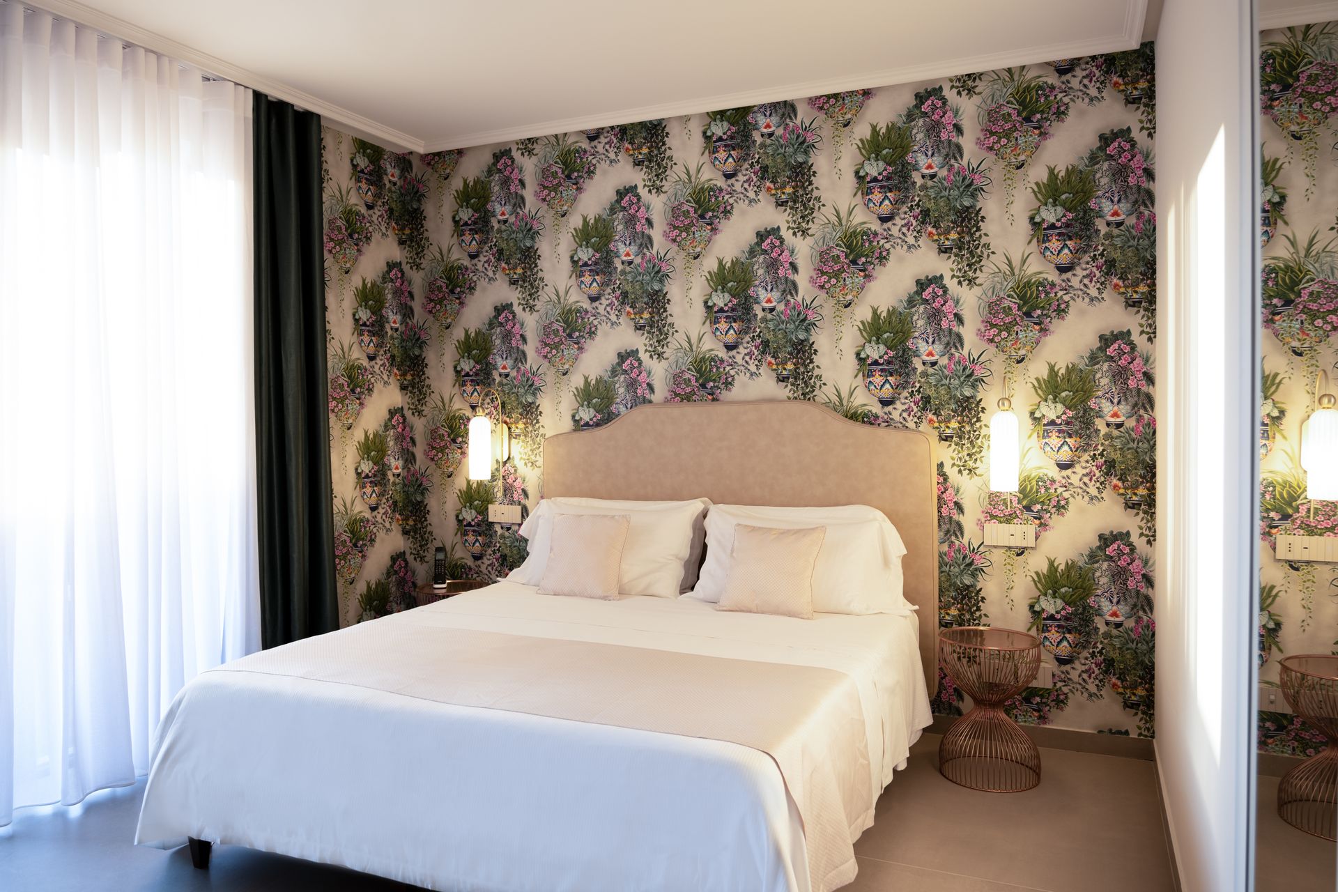 Ein Hotelzimmer mit einem großen Bett und einer Blumentapete an der Wand.