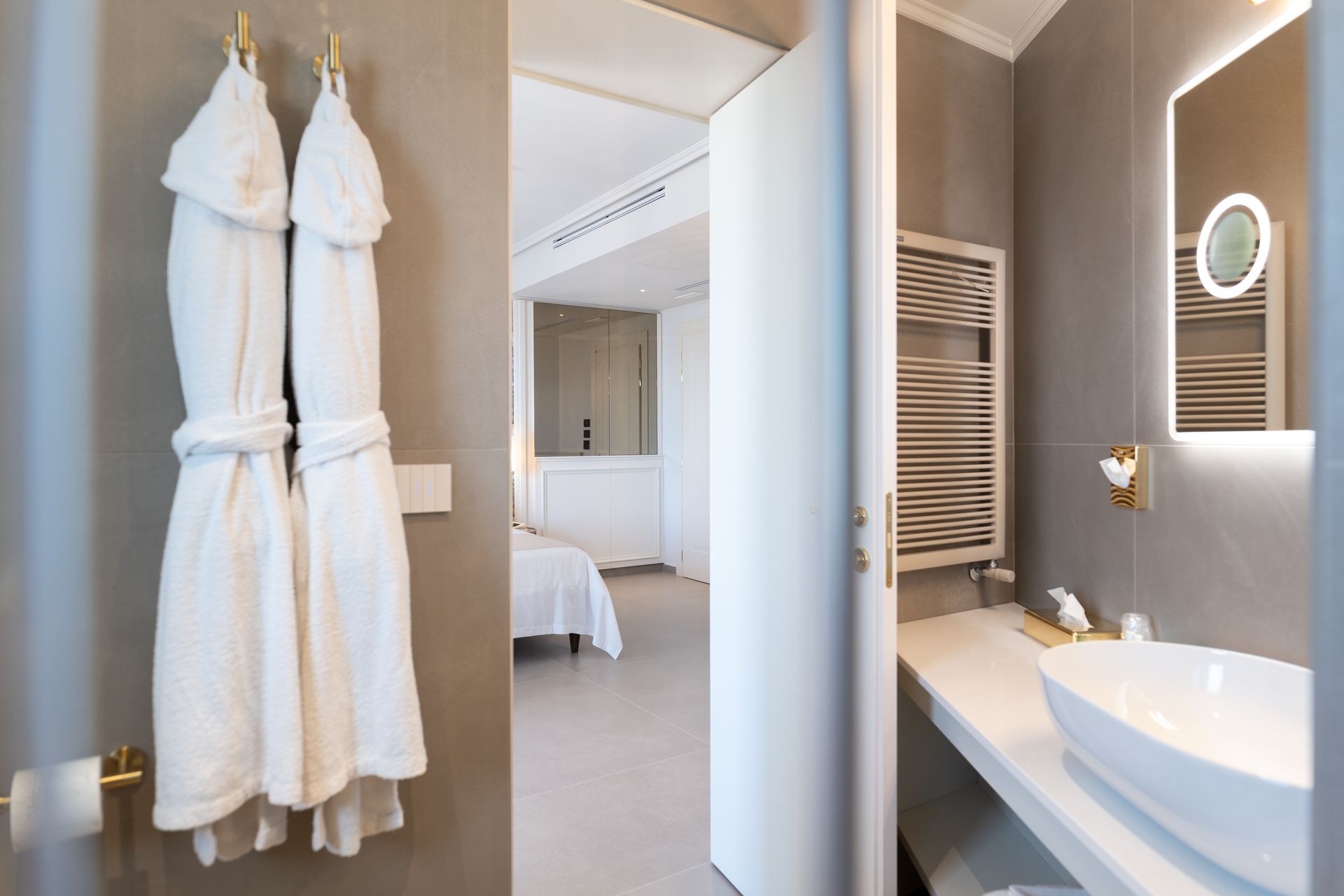 Ein Badezimmer mit zwei an der Wand hängenden Bademänteln und einem Waschbecken.