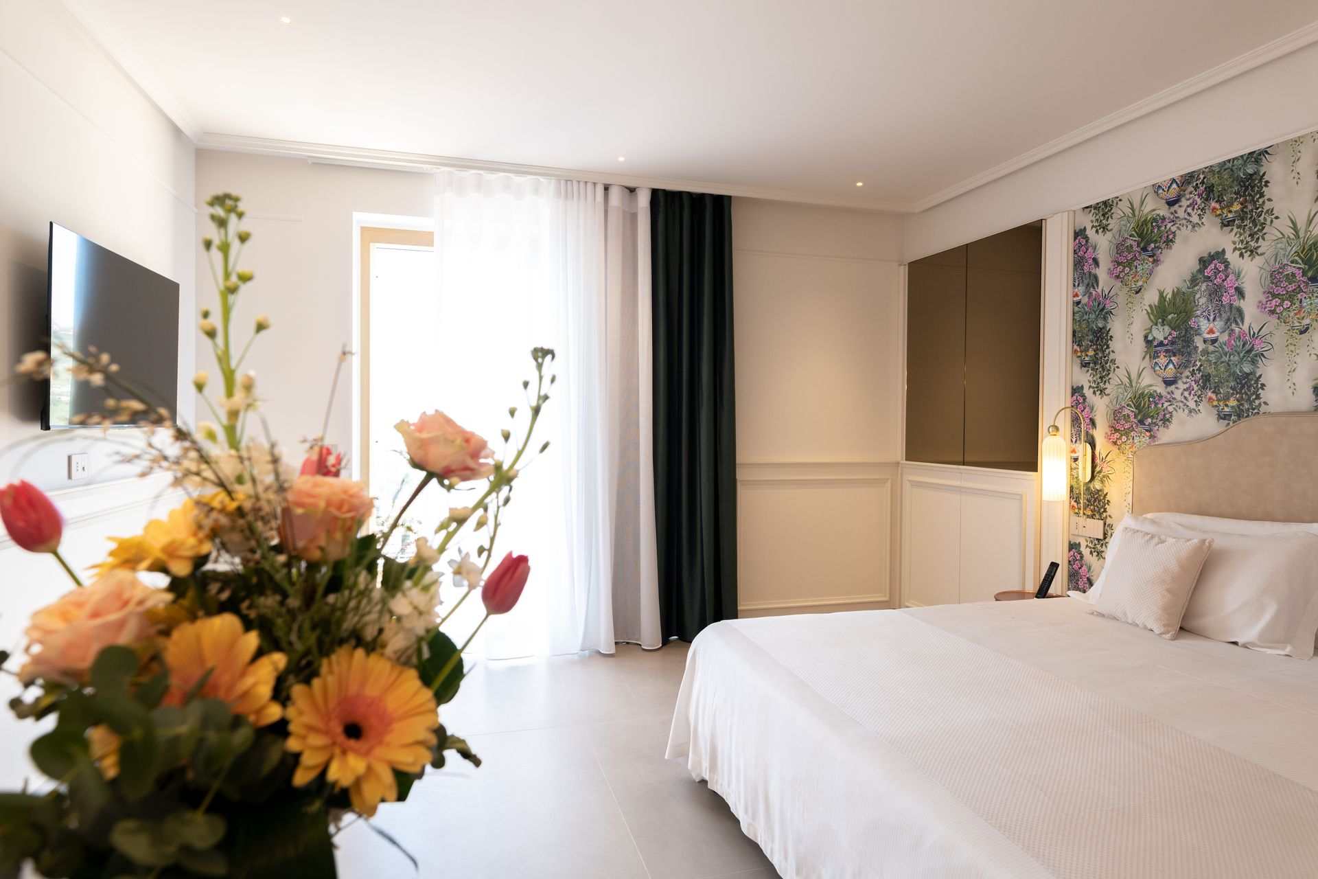 Ein Hotelzimmer mit einem Bett, einem Fernseher und einer Vase mit Blumen.