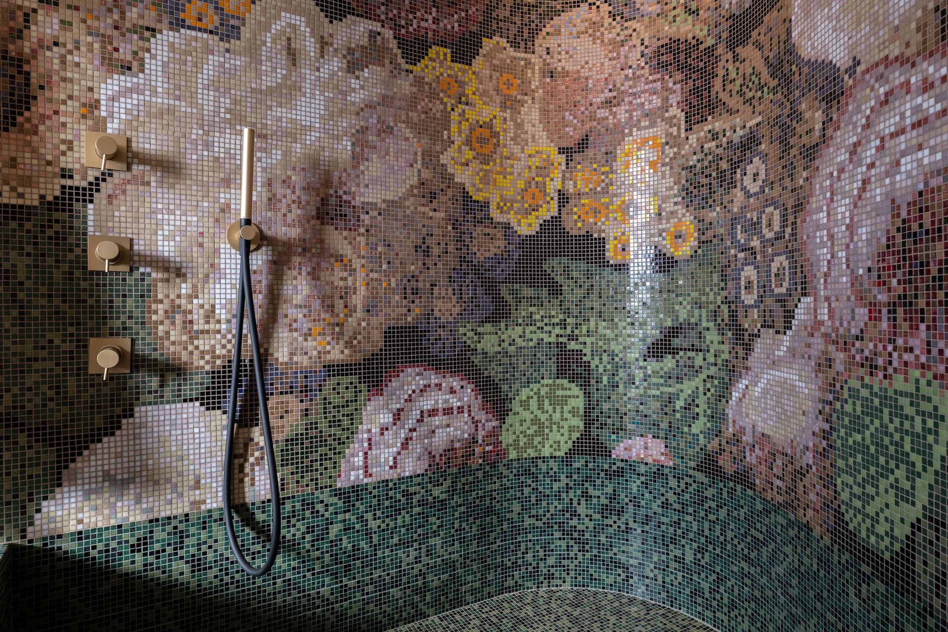 Ein Badezimmer mit Mosaikwand und Duschkopf.