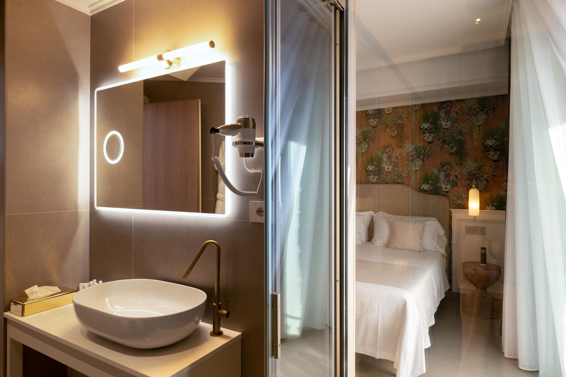 Ein Badezimmer mit Waschbecken und Spiegel neben einem Bett.