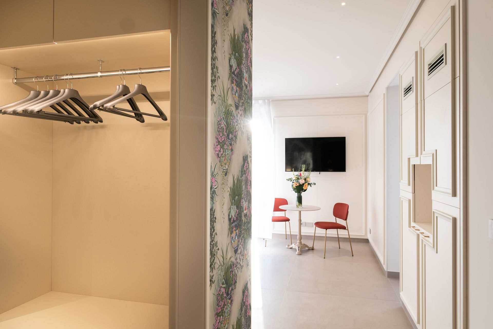 Ein Schrank mit daran hängender Kleidung und ein Wohnzimmer mit einem Tisch und Stühlen.