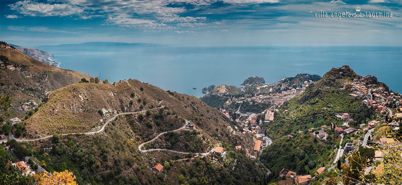 Ein Blick auf eine Stadt von der Spitze eines Berges mit Blick auf den Ozean.
