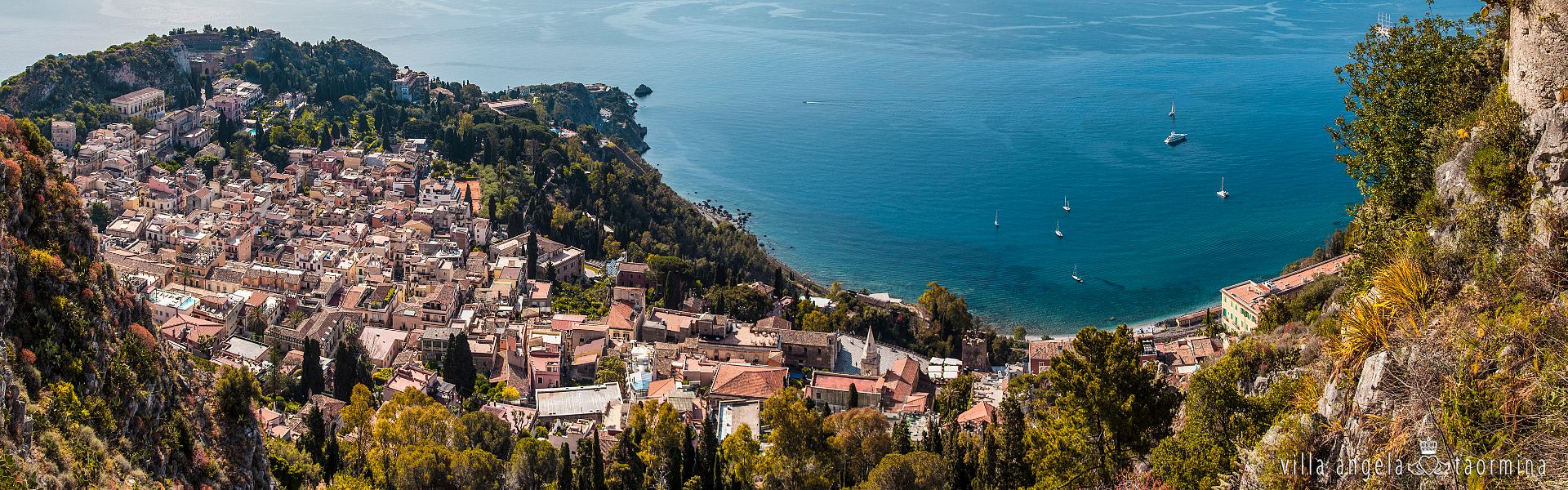 Eine Luftaufnahme einer kleinen Stadt auf einem Hügel mit Blick auf ein Gewässer.