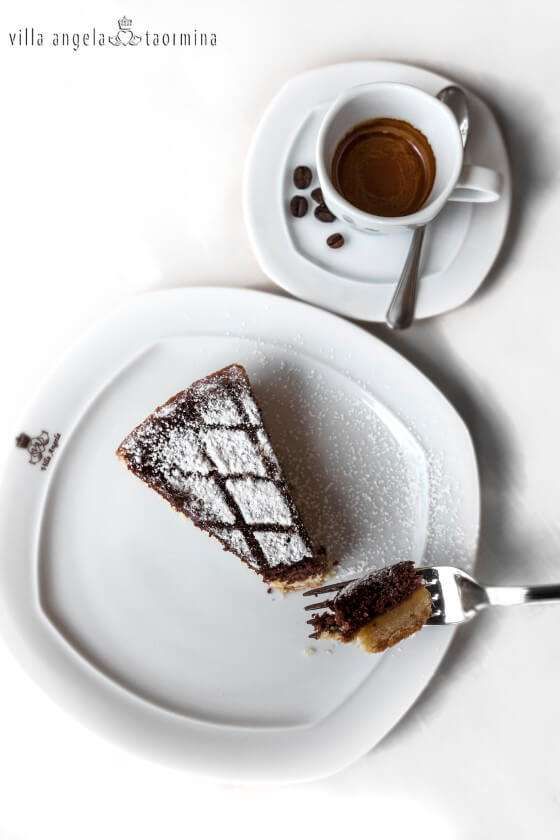 A slice of cake on a plate next to a cup of coffee