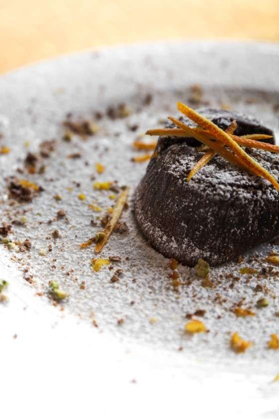 A close up of a chocolate cake on a plate with powdered sugar.