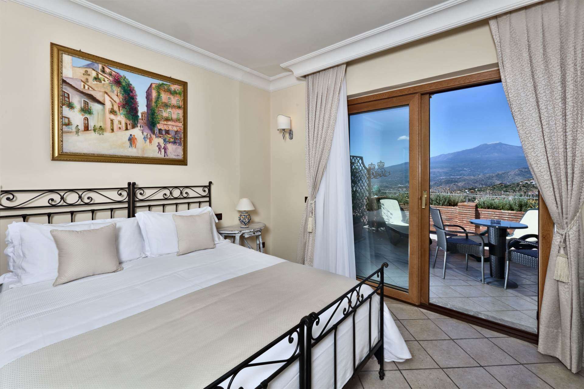 A bedroom with a large bed , sliding glass doors and a painting on the wall.