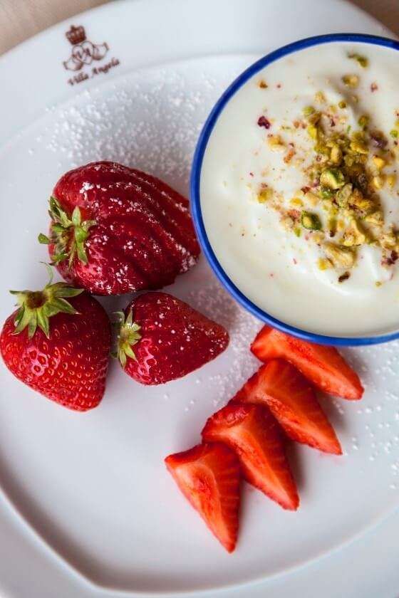 Strawberries and a bowl of yogurt on a white plate
