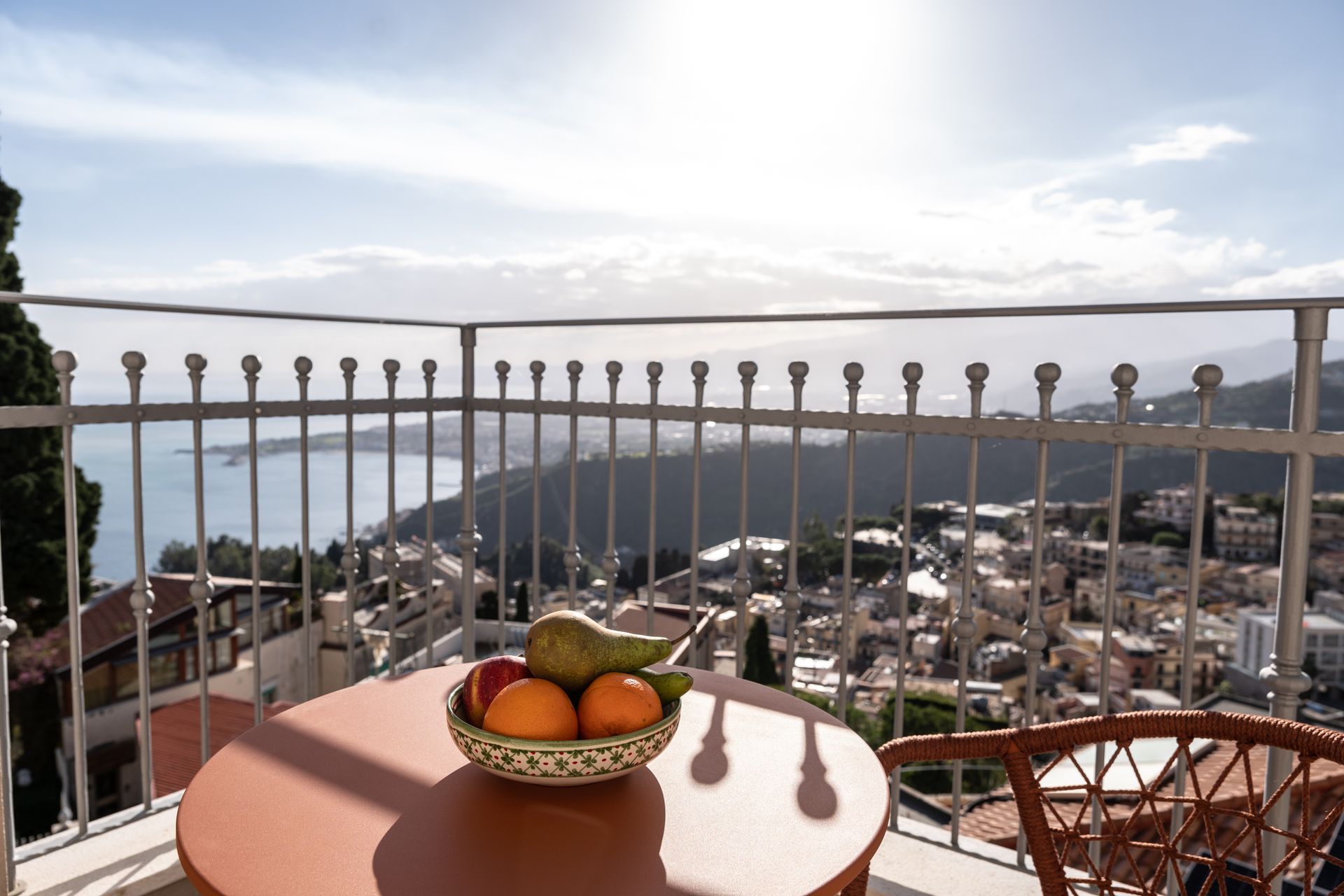 Un bol de fruits est posé sur une table sur un balcon surplombant une ville.