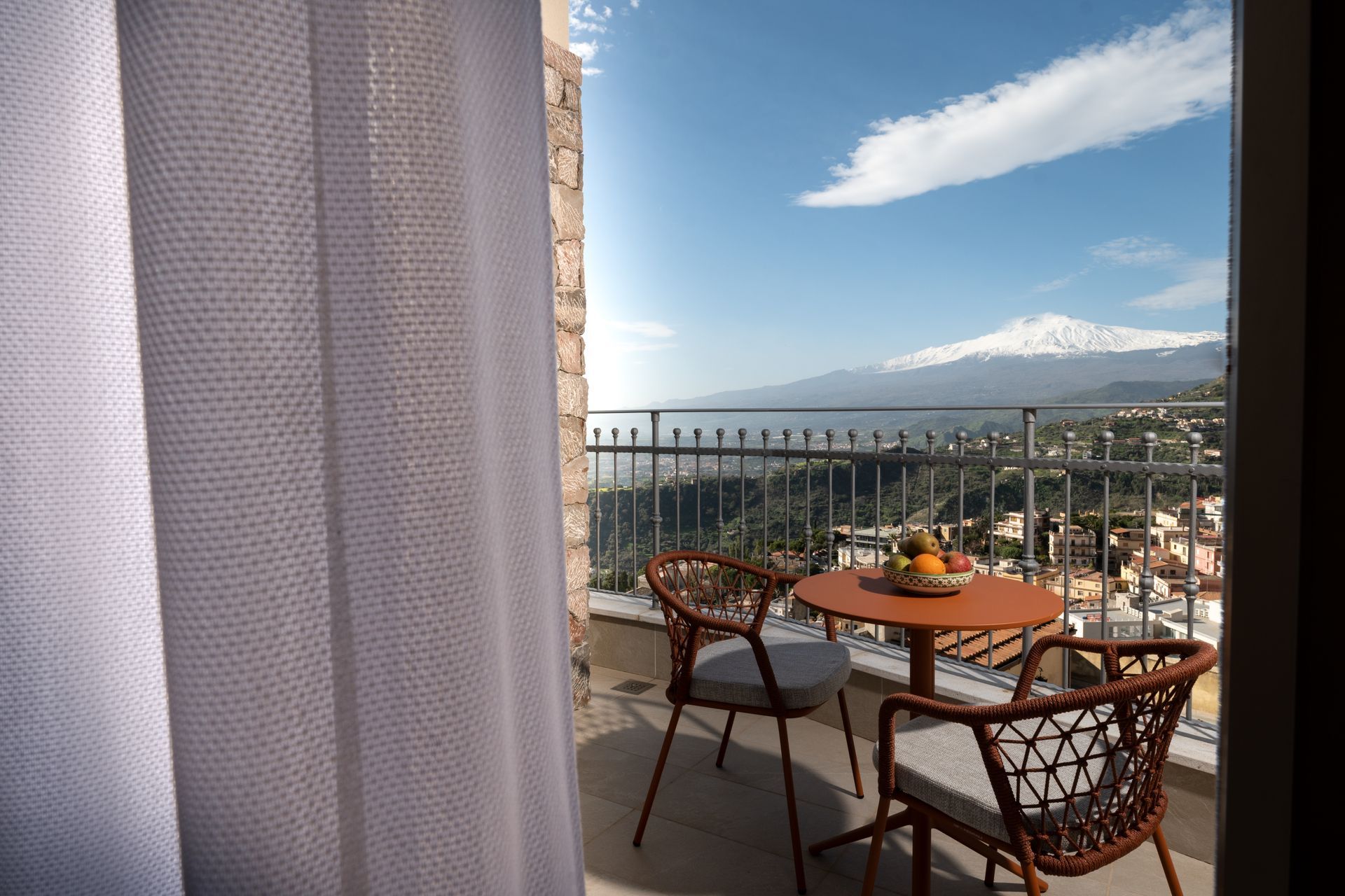 A balcony with a table and chairs and a view of a city.