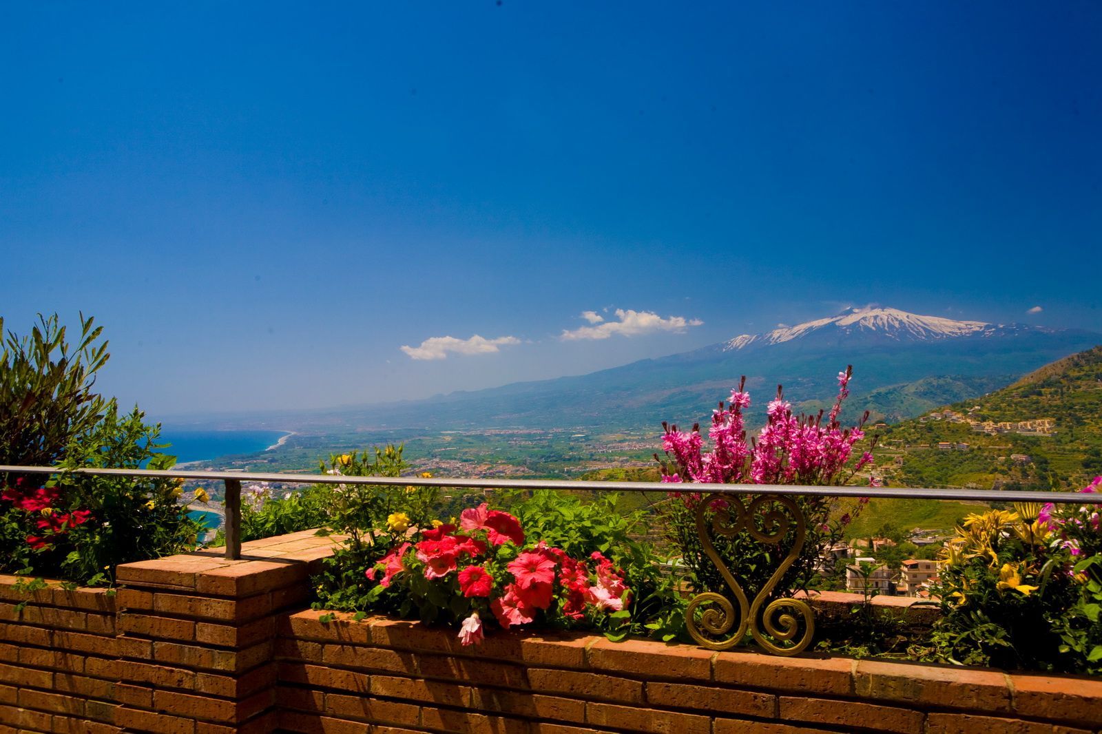 A balcony with flowers and mountains in the background